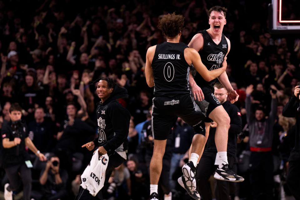 Bearcats guards Simas Lukosius (41) and Dan Skillings Jr. celebrate after they defeated Xavier 68-65 Saturday afternoon at Fifth Third Arena.