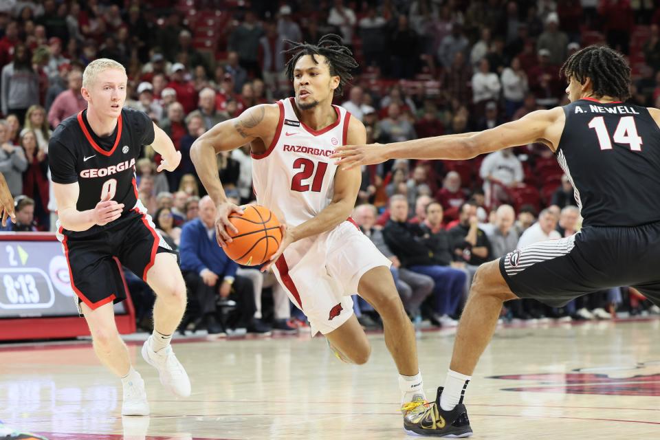 Jan 22, 2025; Fayetteville, Arkansas, USA; Arkansas Razorbacks guard D.J. Wagner (21) drives against Georgia Bulldogs guard Blue Cain (0) and forward Asa Newell (14) during the second half at Bud Walton Arena. Arkansas won 68-65. Mandatory Credit: Nelson Chenault-Imagn Images